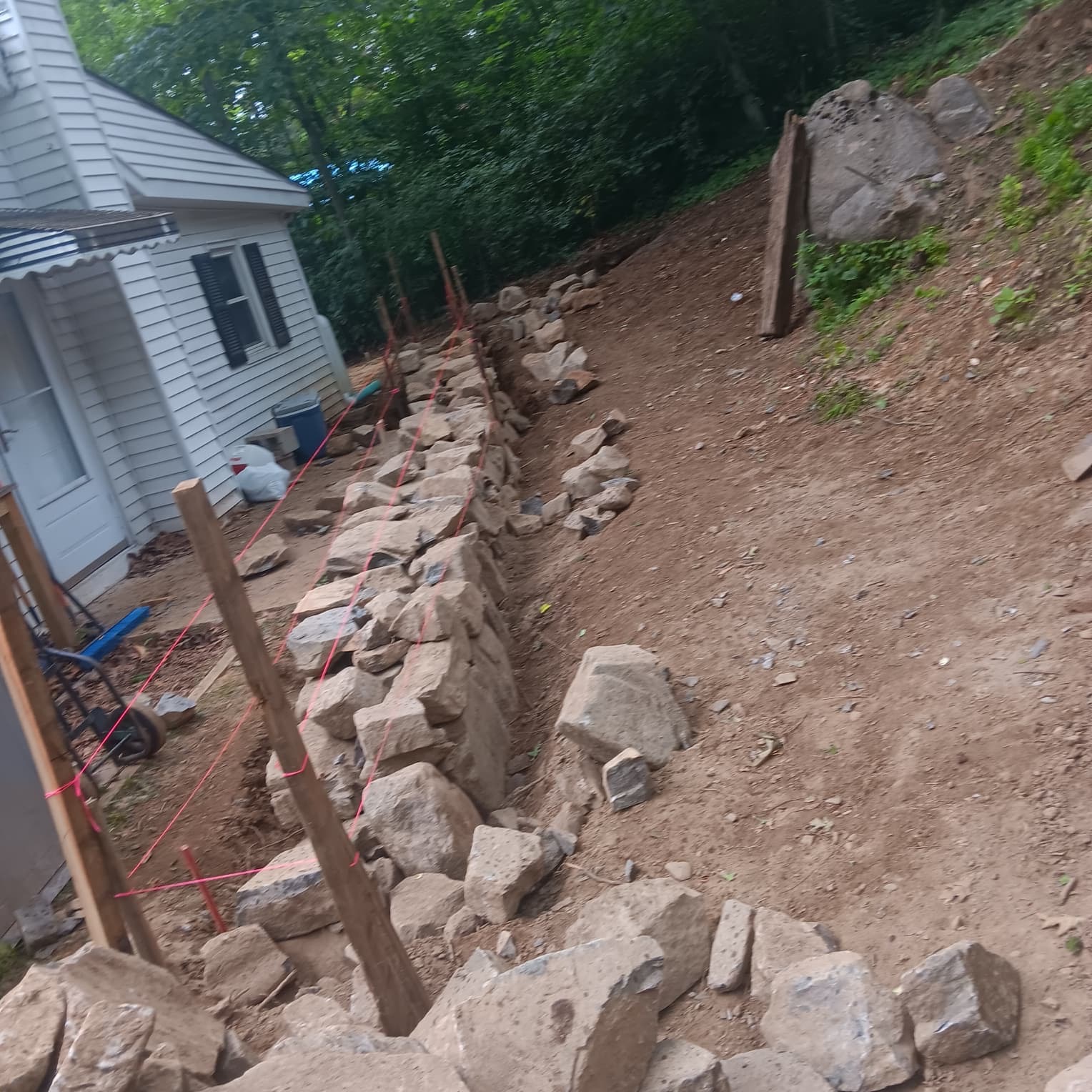 Stone retaining wall construction on slope