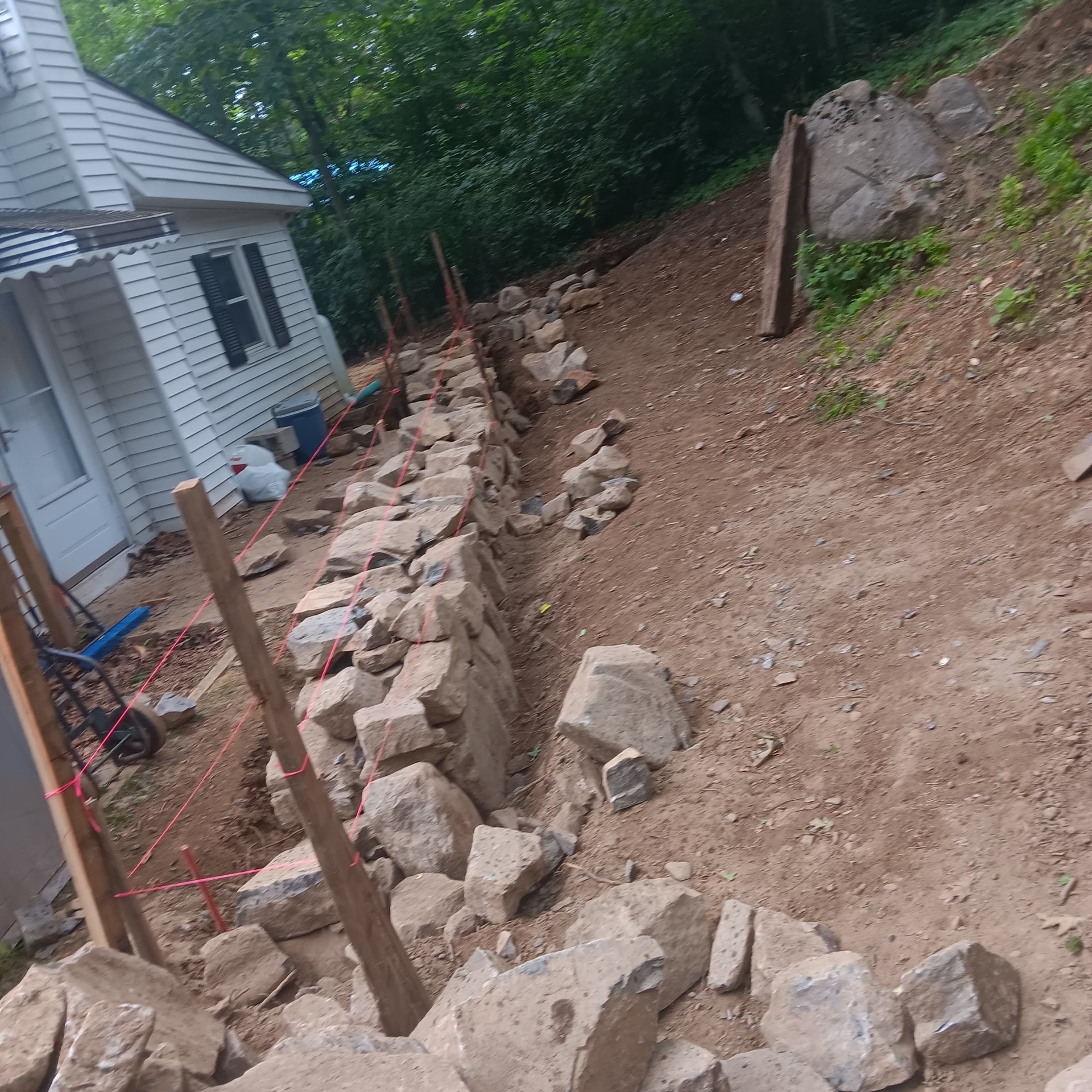 Long fieldstone retaining wall along hillside