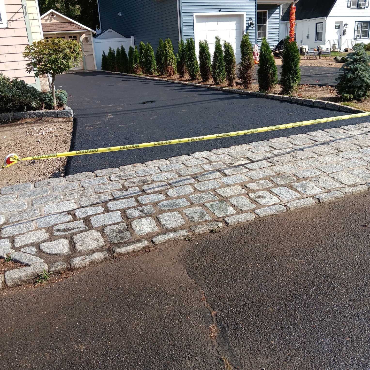Freshly paved asphalt driveway with cobblestone apron