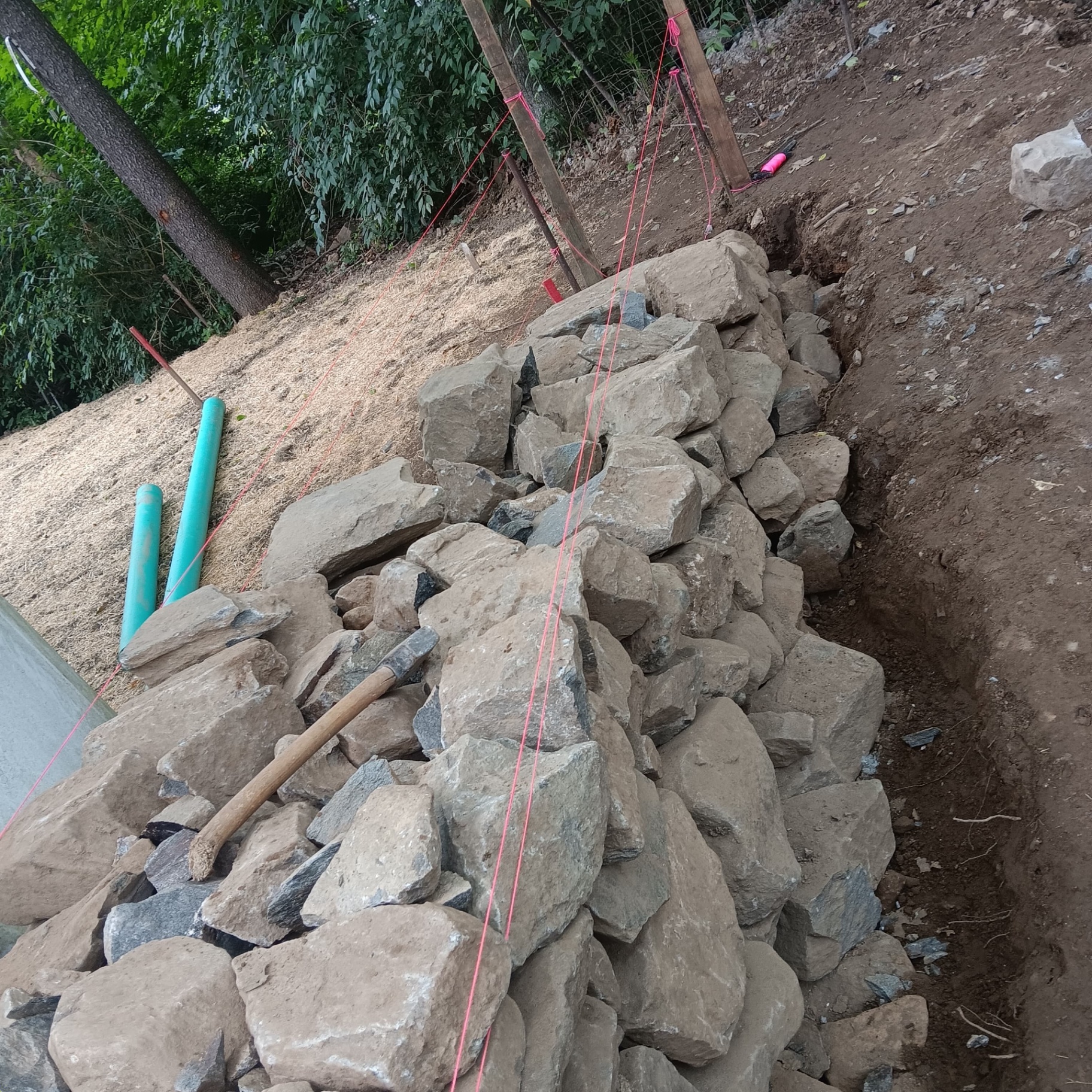 Fieldstone retaining wall on hillside with drainage