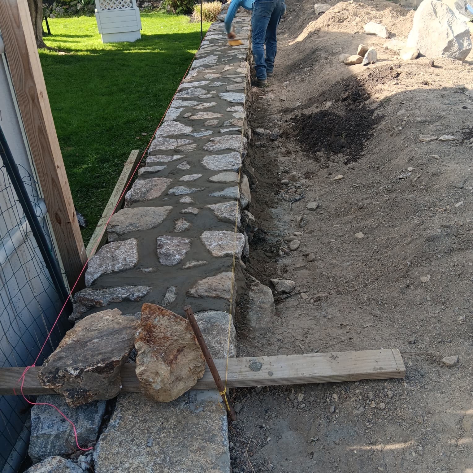 Stone retaining wall being mortared and finished