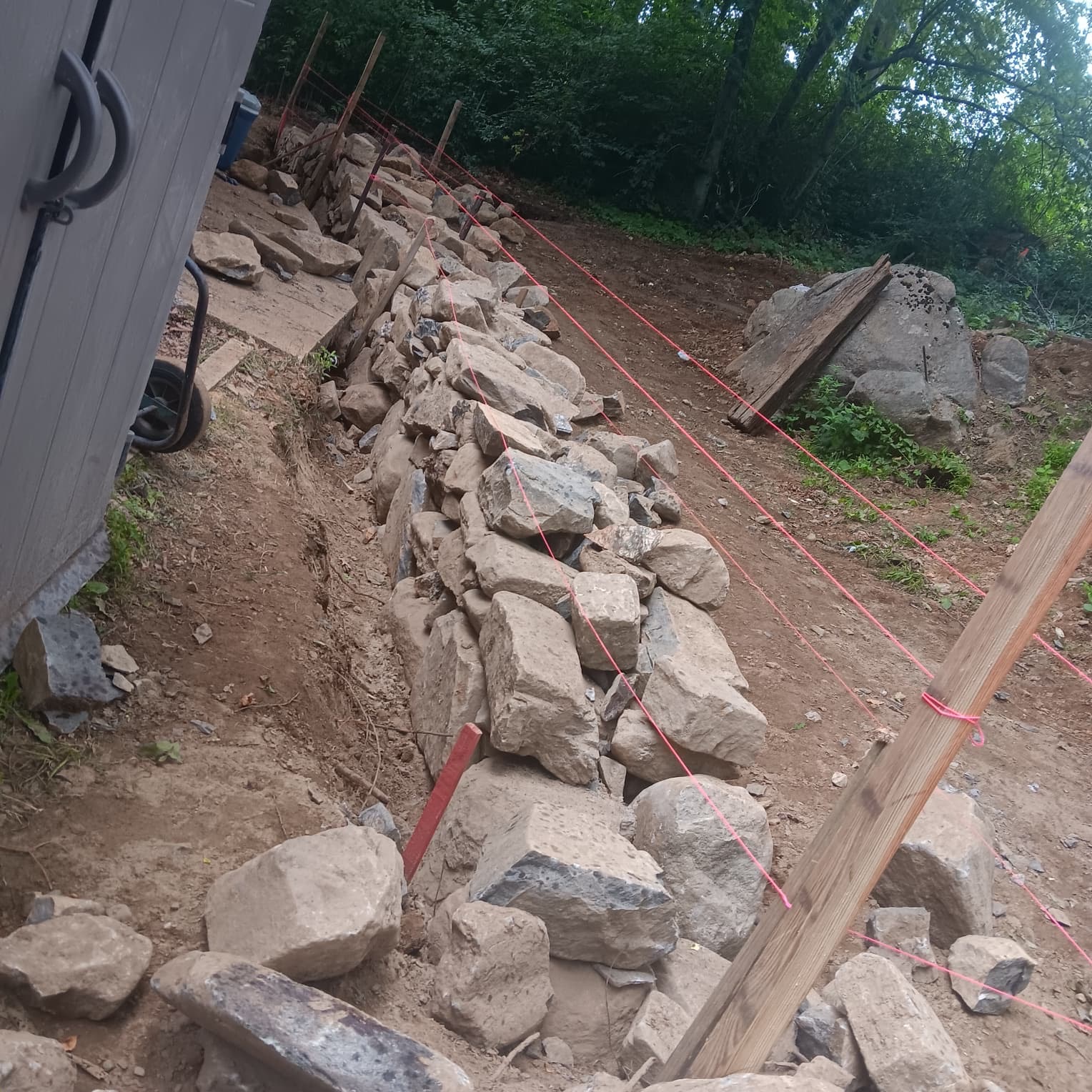 Stone retaining wall along hillside near shed